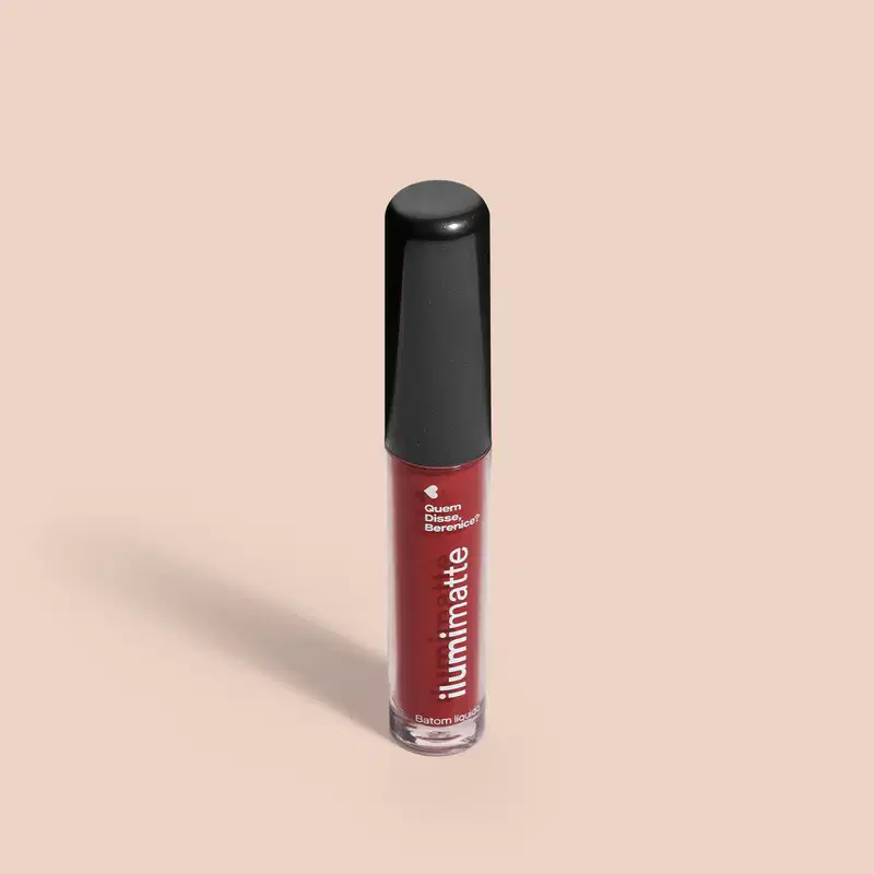 Frasco de 4ml contendo batom líquido vermelho Vermelumi Ilumimatte da marca Quem Disse, Berenice? em embalagem transparente mostrando o produto na cor marrom, tampa preta e letras brancas em fundo rosado com leve sombreado.