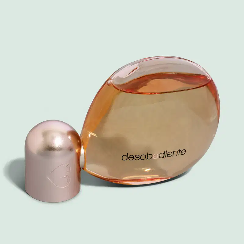 Frasco com líquido rosa e detalhes rose gold contendo 100ml de Eau de Parfum Desobediente Quem Disse, Berenice? em fundo azul claro.