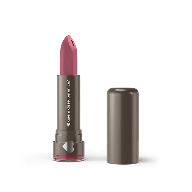 Um item de perfumaria rosa em formato de batom com embalagem metálica cinza. O rótulo exibe o texto "Quem Disse, Berenice?" em letras brancas.