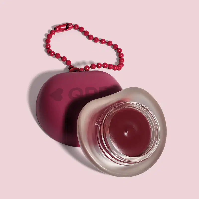 Recipiente roxo com logotipo em forma de coração, O recipiente está sobre um fundo rosa. A imagem sugere um ambiente relacionado a produtos de beleza e cuidados pessoais.