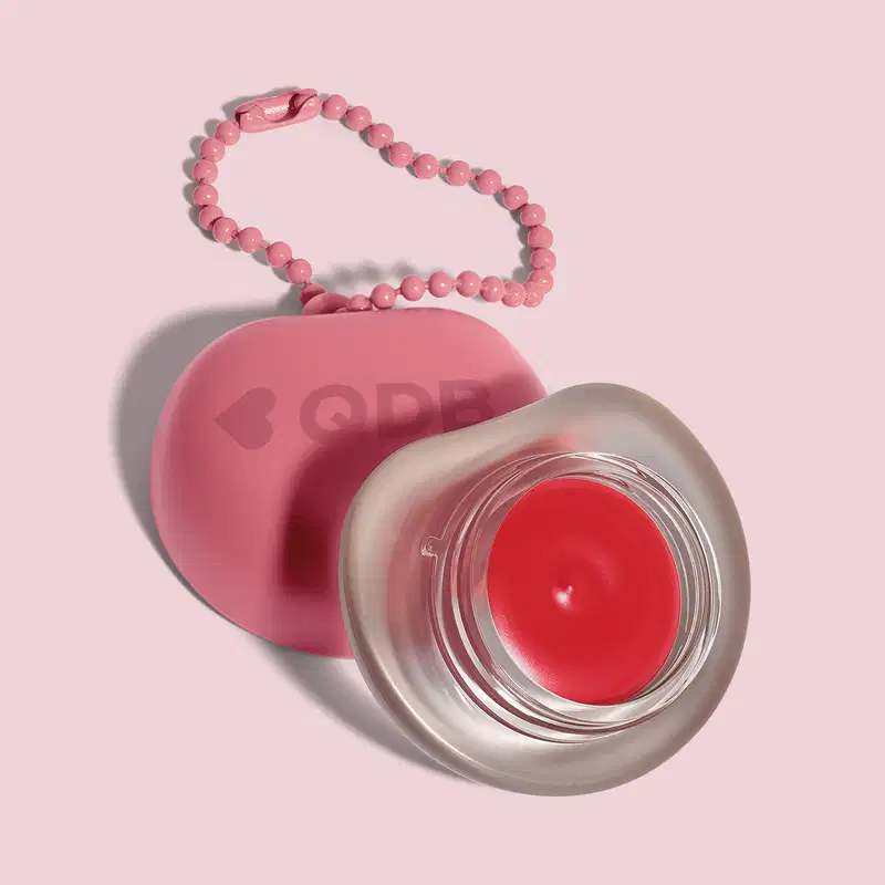 Recipiente rosa com logotipo em forma de coração, O recipiente está sobre um fundo rosa. A imagem sugere um ambiente relacionado a produtos de beleza e cuidados pessoais.