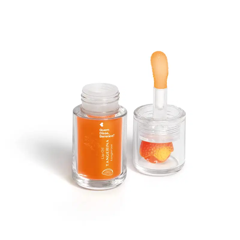 Frasco de vidro com tampa contendo um líquido laranja e um aplicador em formato de esponja. Rótulo com texto "Quem disse, Berenice?" e "Lip oil Tangerina". Embalagem transparente com produto de beleza em formato de óleo labial.