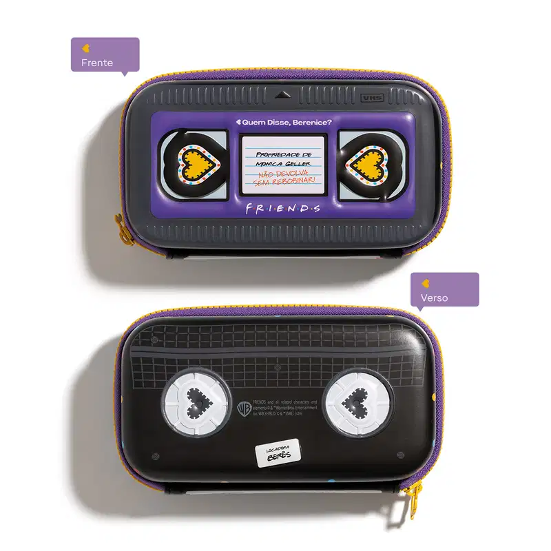 Acessório com design inspirado na série de TV "Friends". Imita fita VHS com uma mensagem sobre não devolver algo sem recarregar. Possui detalhes em roxo e amarelo, com ícones de coração em ambos os lados e no verso do item.