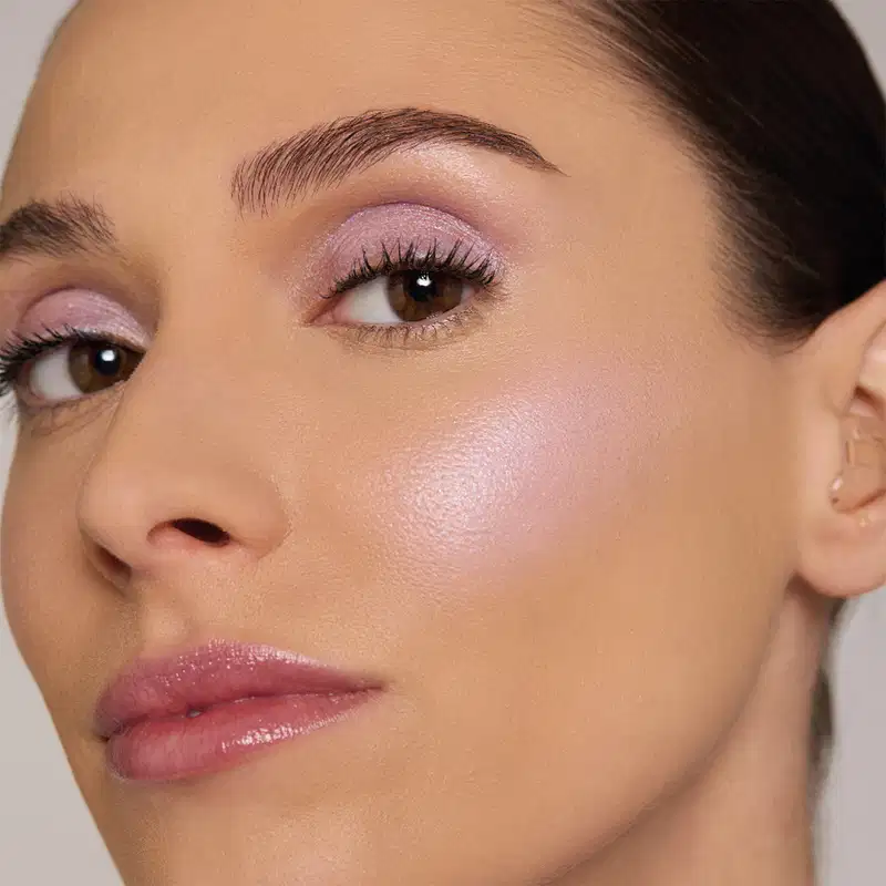 Frasco de iluminador da marca Quem Disse, Berenice? em embalagem rosa clara com texto branco "NAH" e coração. Aplicador de espuma na ponta para aplicação suave do produto.