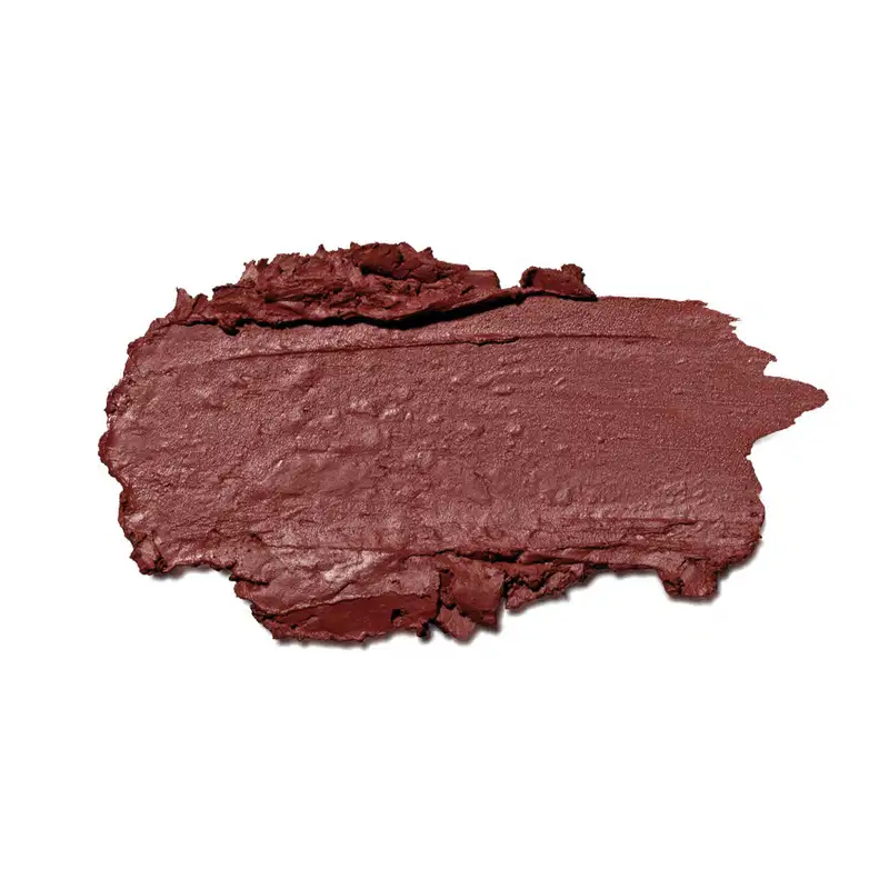 A textura do produto de beleza apresenta uma superfície irregular e áspera, com uma coloração marrom avermelhada predominante. A consistência parece ser cremosa e levemente brilhante, com uma aparência de material compactado.