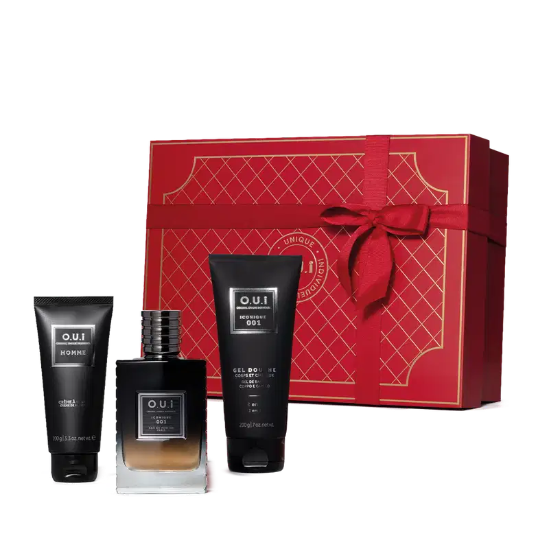 Conjunto. No centro, frasco de vidro contendo líquido da fragrância em degradê de preto à âmbar, de alto a baixo. Ao lado, tubo preto de gel de banho e um tubo preto de creme de barbear. Acompanha caixa vermelha com detalhes em dourado e laço vermelho.