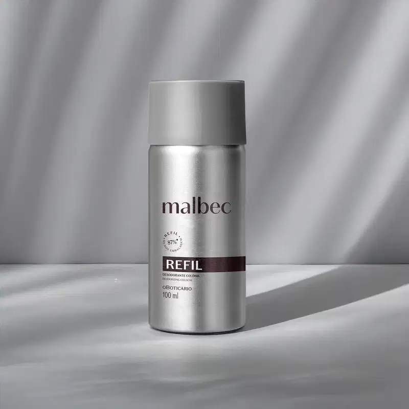 Imagem de um refil de metal prateado de desodorante colônia com rótulo da marca Malbec em fundo cinza, em ambiente minimalista e monocromático.