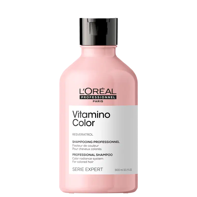 Frasco de plástico rosa com tampa preta. Rótulo com texto "L'OREAL PROFESSIONNEL PARIS Vitamino Color" e "SHAMPOOING PROFESSIONNEL". Produto de cuidados capilares para cabelos coloridos.