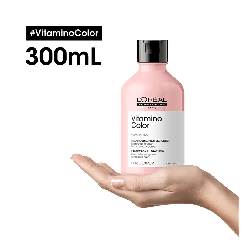 Frasco de 300 mL de shampoo da marca L'Oréal Professionnel, da linha Vitamino Color. O frasco é rosa claro com rótulo branco e preto, exibindo o nome do produto e a hashtag "#VitaminoColor".