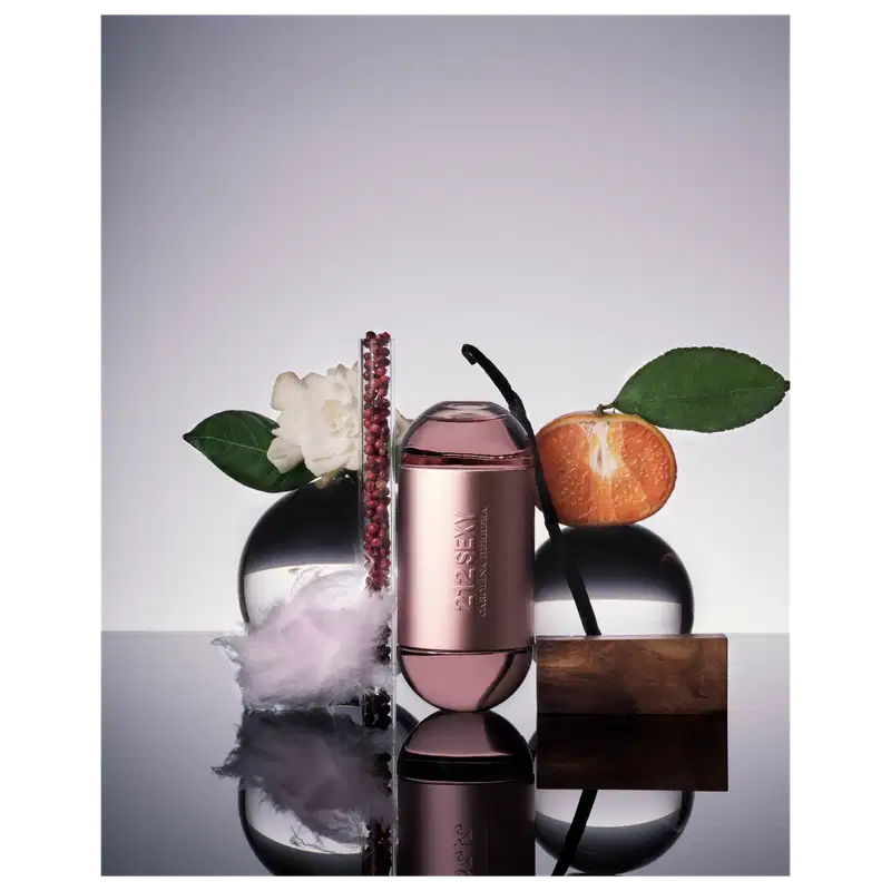 Frasco de perfume Carolina Herrera 212 Sexy, com formato cilíndrico e tampa arredondada, em tons de rosa claro. O rótulo exibe o nome da fragrância em letras prateadas.