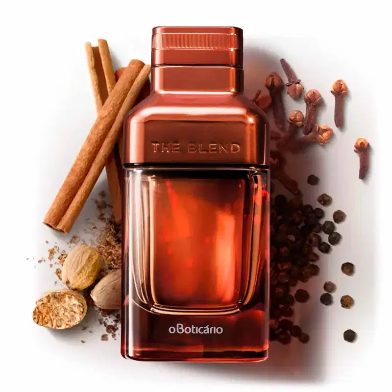 Vidro em tom de marrom fosco com detalhes em marrom metalizado e letras azuis contendo Eau de Parfum The Blend cercado por canela em pau, noz-moscada, cravo-da-índia e sementes de pimenta sobre superfície branca.