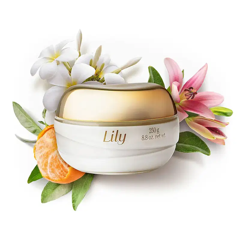 Pote de vidro transparente com conteúdo branco, tampa e letras douradas de creme acetinado hidratante desodorante corporal da marca Lily rodeado por lírios, flores brancas, folhas verdes e gomos de bergamota.