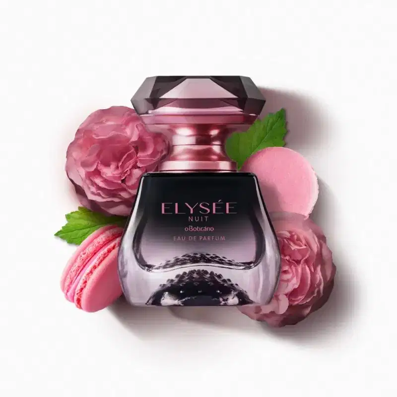 Vidro transparente em preto e transparente com borrifador e letras douradas, tampa transparente em formato de cristal lapidado de Eau de Parfum Elysée Nuit circundado por flores rosas, macarons rosa e folhas verdes sobre fundo branco.