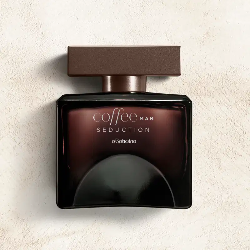 Frasco quadrado marrom com tampa retangular na mesma cor e letras cinzas, contendo desodorante colônia Coffee Man Seduction em fundo cinza com sombras.