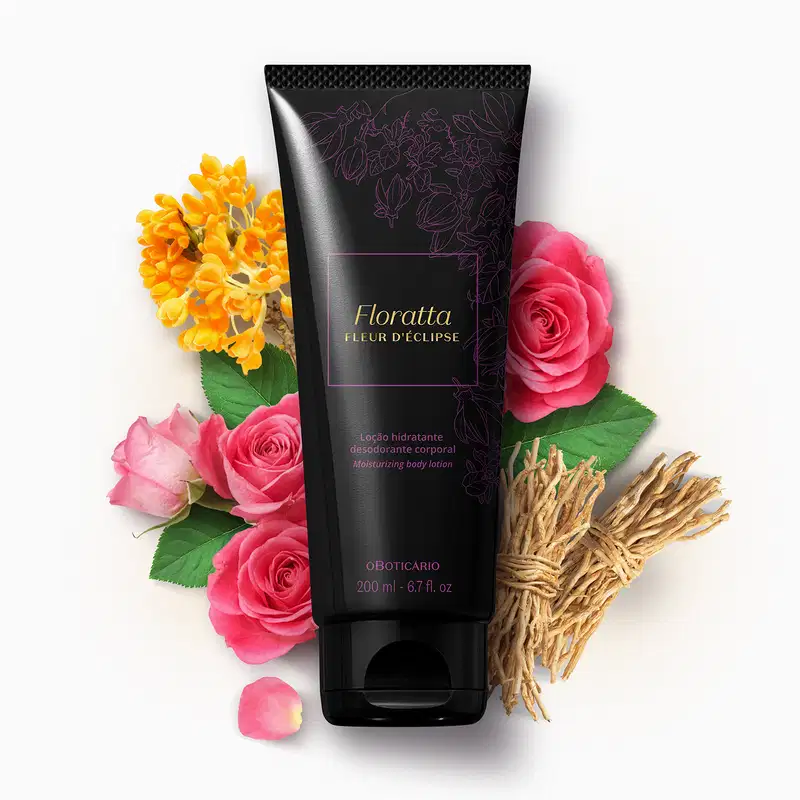 Bisnaga preta com letras e detalhes dourados contendo 200g de loção hidratante corporal Floratta Fleur d' Éclipse cercado por rosas rosa, flores amarelas, galhos secos e pétalas sobre fundo branco.