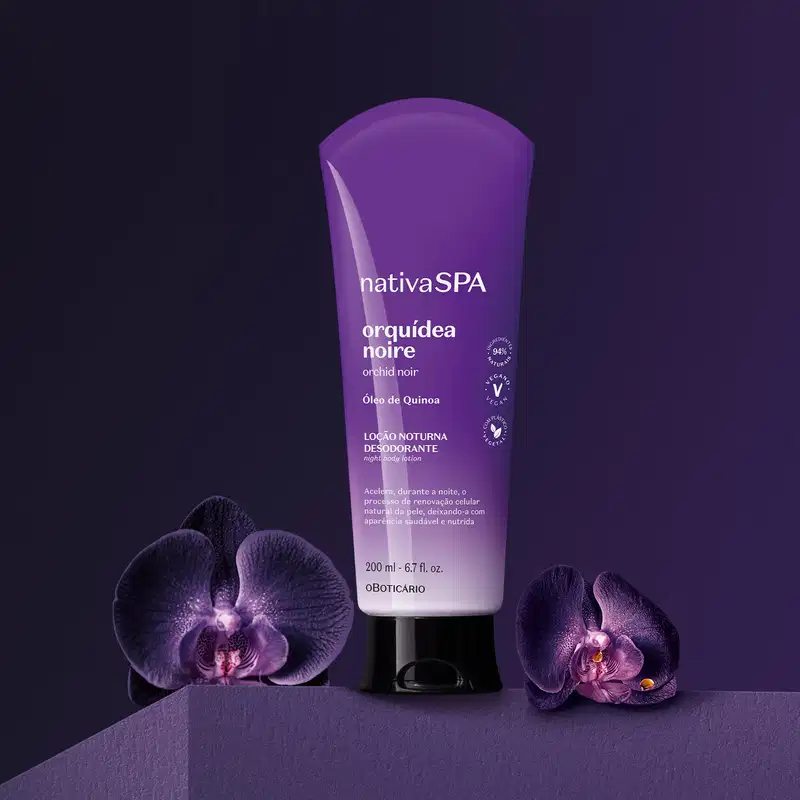 Bisnaga com degradê de roxo e branco, tampa preta e letras douradas e brancas contendo 200ml de loção noturna corporal Nativa SPA Orquídea Noire está em fundo escuro com orquídeas roxas ao redor.
