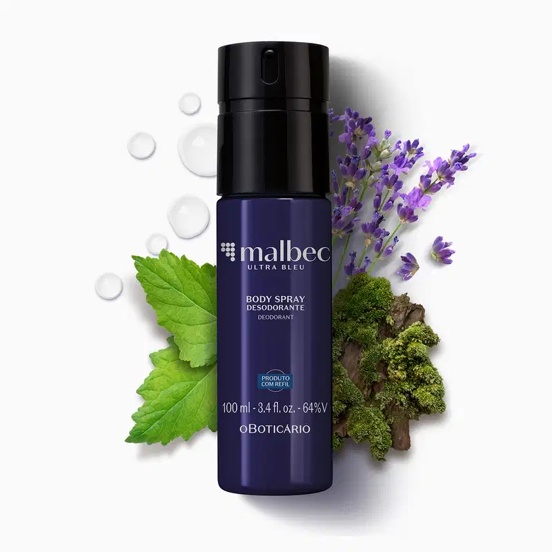Frasco azul escuro com letras cinzas contendo 100ml de body spray Malbec Ultra Bleu, cercado por gotas de água, folhas verdes, flores roxas de lavanda e musgo em fundo branco.