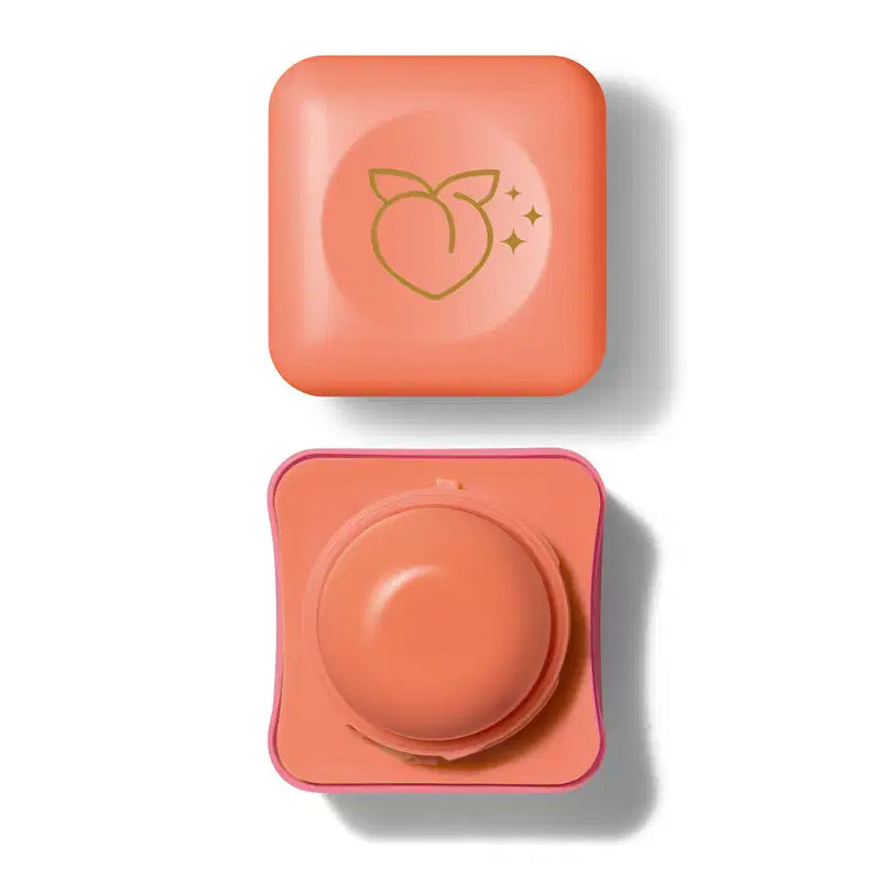 Pote compacto com cantos arredondados nas cores rosa e laranja com roll-on laranja e tampa laranja com ilustração de um pêssego contendo hidratante labial Intense & Cuide-se Bem Leite e Mel.