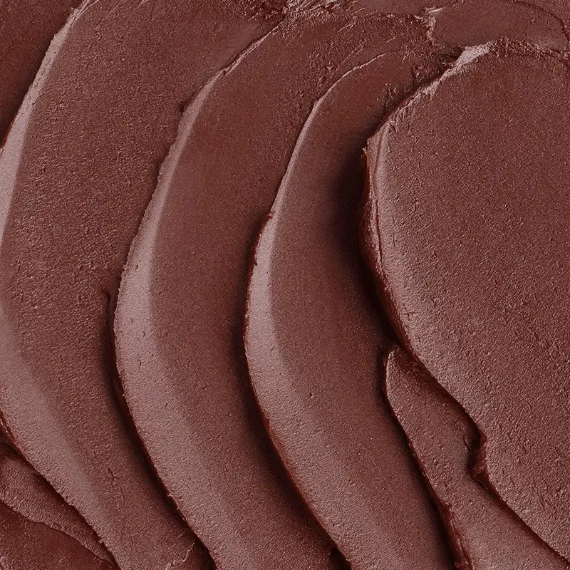Textura cremosa de tom marrom escuro com acabamento aveludado e brilho sutil, em superfície lisa e uniforme do batom hidratante na cor Marrom Marronito da marca Quem Disse, Berenice?.