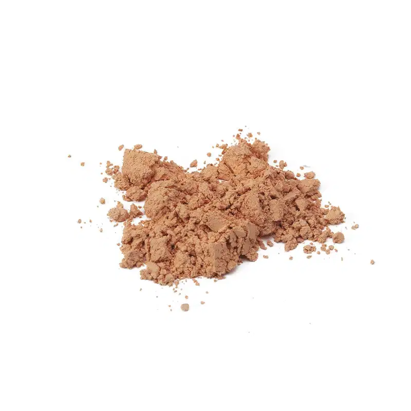 Pó solto em tom bege escuro com textura granulada e particulada, disperso sobre superfície branca, sugerindo se tratar da base em pó mineral cor 30 da marca Make B.