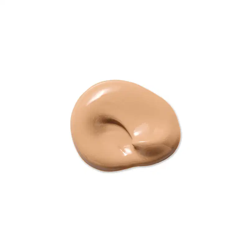 Textura de base líquida bege, com aspecto cremoso e brilhante, espalhada em formato orgânico sobre fundo branco liso, exibindo sombras suaves e pequenos reflexos de luz.