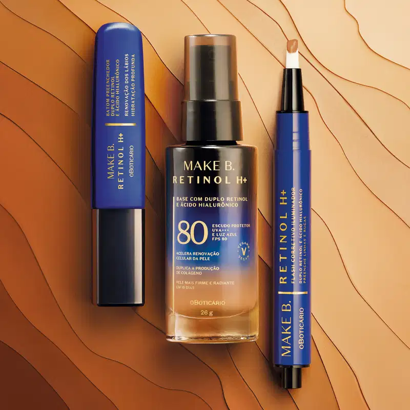 Três produtos Make B. Retinol H+, sendo batom preenchedor à esquerda, base com FPS 80 ao centro e corretivo iluminador à direita. As embalagens têm tons de azul e preto e o fundo é feito com diferentes tons de base espalhados e maneira orgânica.