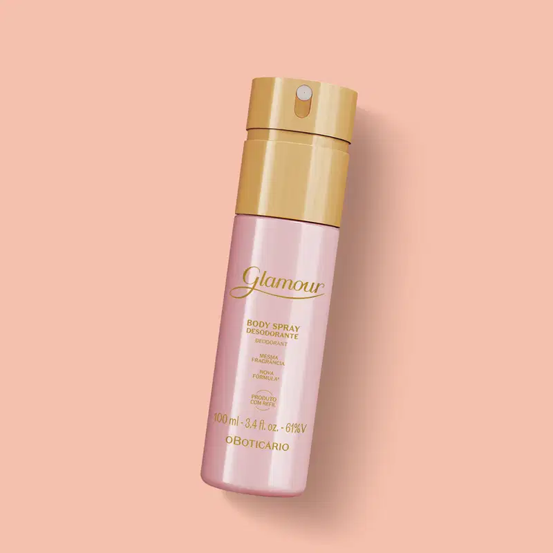 Frasco rosa com tampa e letras douradas contendo 100ml de body spray Glamour sobre fundo rosa.