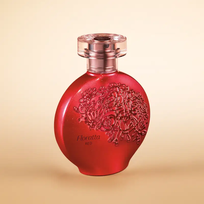 Perfume em frasco de vidro vermelho com detalhes em relevo floral. O frasco tem um formato arredondado e tampa rosada metálica. O frasco vermelho vibrante e os detalhes florais em alto relevo, sugerindo uma fragrância floral intensa.