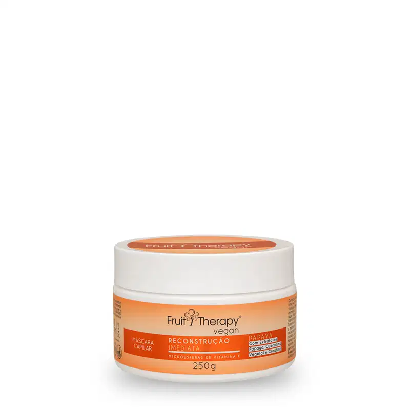 A imagem mostra a máscara de reconstrução da linha Fruit Therapy Vegan de Papaya. Ela é embalada em um pote plástico branco de 250g. O rótulo tem um fundo laranja e destaca os benefícios do produto.