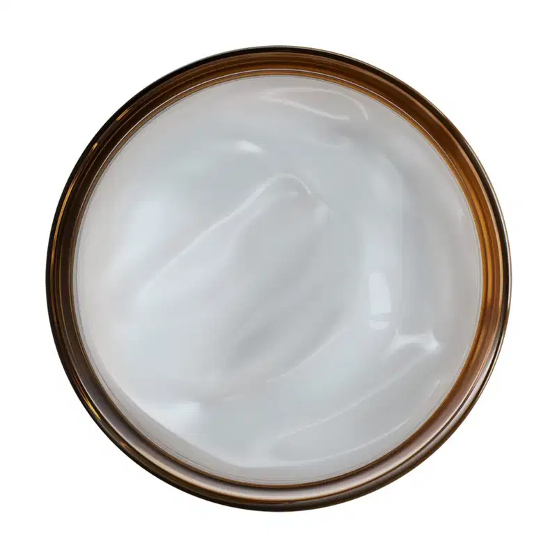 Frasco de creme facial em formato circular, contendo um produto branco e cremoso em seu interior.